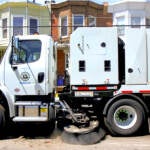 A Streets Department mechanical broom truck drives down a Philadelphia street