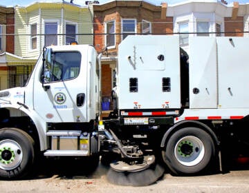 A Streets Department mechanical broom truck drives down a Philadelphia street