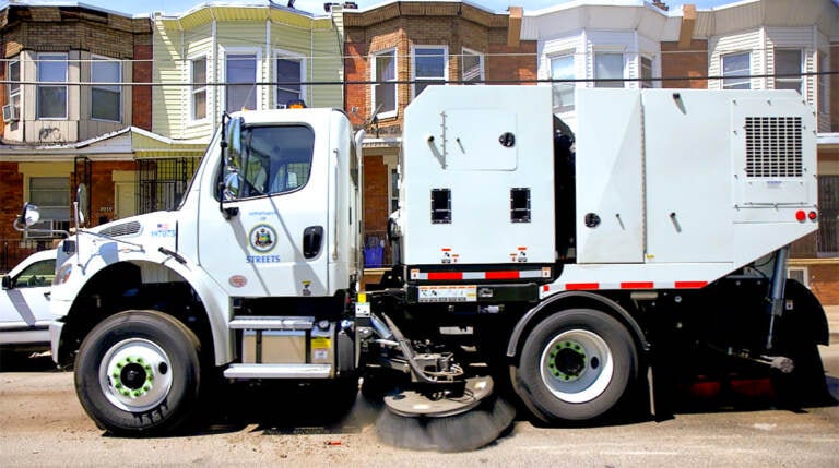 A Streets Department mechanical broom truck drives down a Philadelphia street