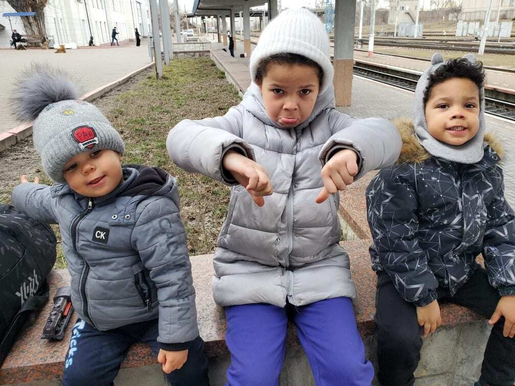 Taras, Zoryana, and Nazar Poladko give a thumbs down at the train station