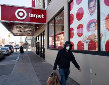 A customer wearing a mask carries his purchases as he leaves a Target store