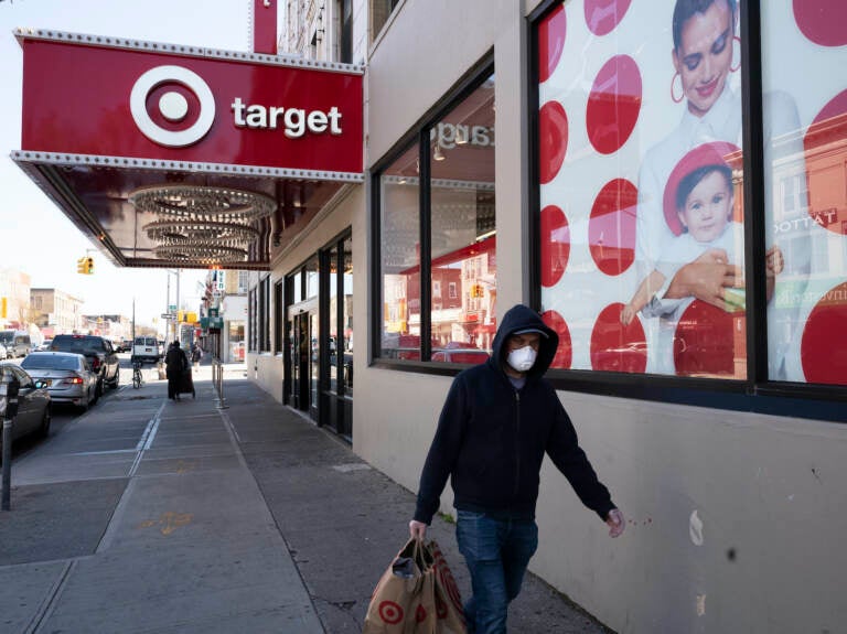 A customer wearing a mask carries his purchases as he leaves a Target store