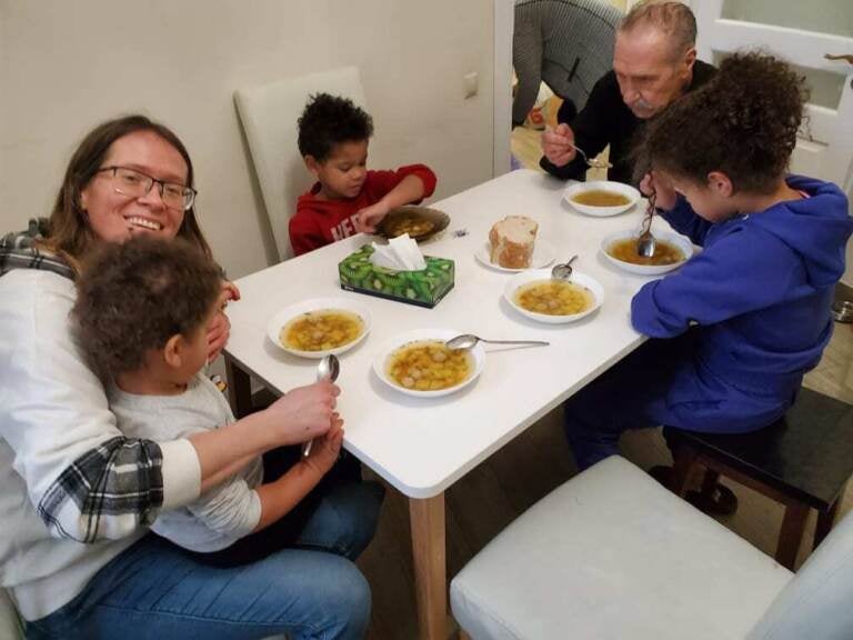 Tatiano Poladko and her father sit at a table eating with Tatiana's three children