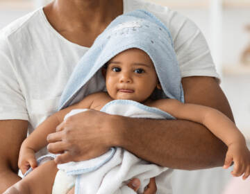 A baby wrapped in a towel and held by a man