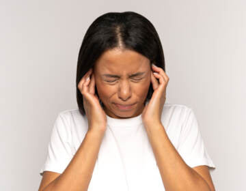 A young woman plugging her ears to block out noise