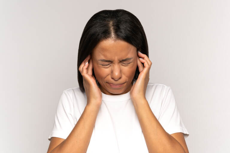 A young woman plugging her ears to block out noise