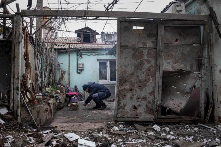 A man lights a fire under the kettle in a yard of an apartment building hit by shelling