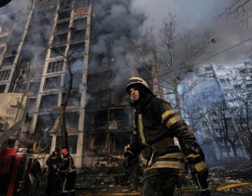 A firefighter walks outside a destroyed apartment building after a bombing in a residential area in Kyiv