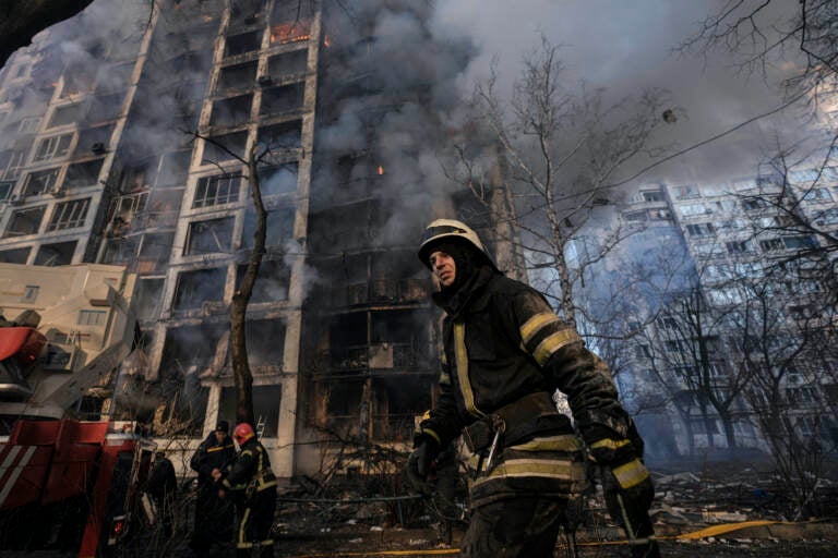 A firefighter walks outside a destroyed apartment building after a bombing in a residential area in Kyiv