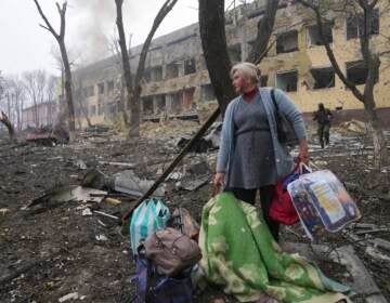 A woman walks outside a maternity hospital that was damaged by shelling in Mariupol