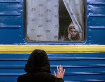 A father waves goodbye to his daughter as she departs on a train to Poland