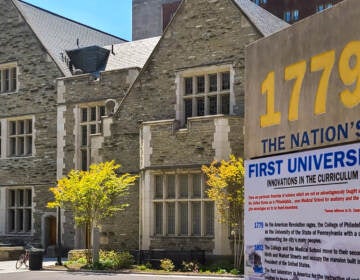 A stone building on the University of Pennsylvania campus is shown behind a sign that reads, 