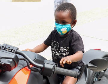 A toddler poses on a stationary bike