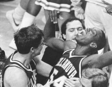 In a black-and-white photo, a group of Villanova basketball players celebrate.