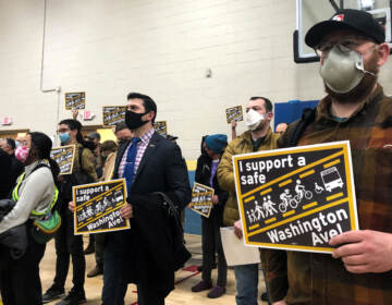 Community members hold signs calling for a safer Washington Avenue