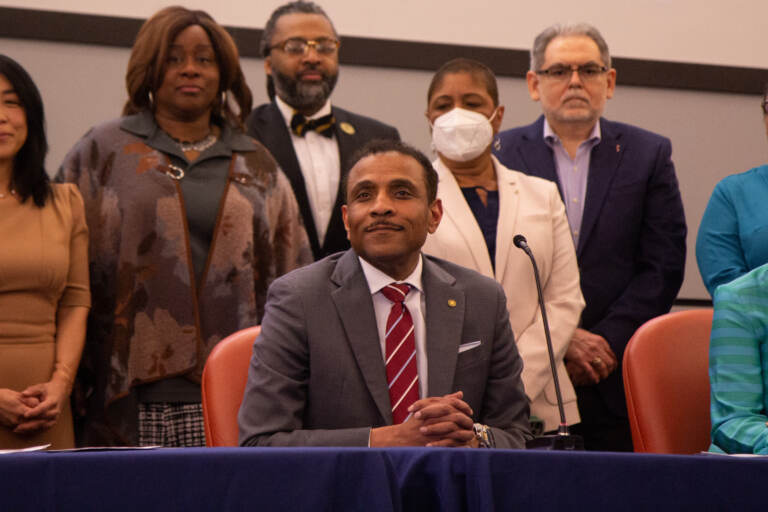 Dr. Tony Watlington sits at a table, with school board officials behind him