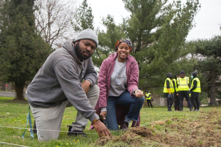 Christa Barfield (right) FarmerJawn founder, and Chief Operating Officer Brandon Ritter (left), help members of PowerCorpPHL learn prepare soil for planting at the Elkins Estate. (Kimberly Paynter/WHYY)