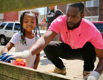 Tyrique Glasgow helps 7-year-old Ryan Penson get started with a paint roller at Tynirah's Community Welcome Garden