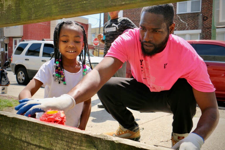 Tyrique Glasgow helps 7-year-old Ryan Penson get started with a paint roller at Tynirah's Community Welcome Garden