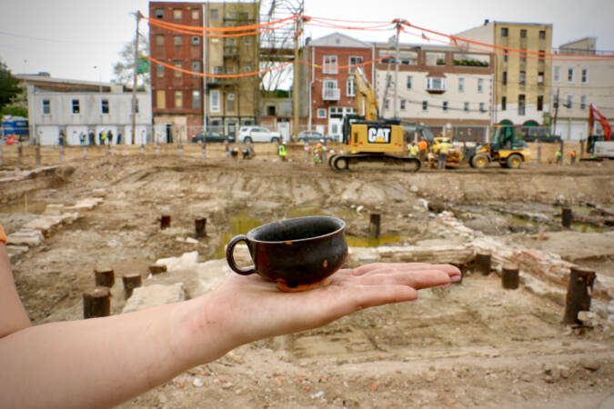 Archaeologist Caitlyn-Jean Ward holds a small porringer, a handled bowl, unearthed at the Columbus and Vine site. This one, made of locally produced redware, was likely a child's toy. (Emma Lee/WHYY)