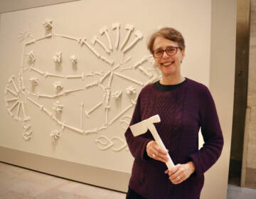 Virginia Maksymowicz holds one of the cast-plastic tools she created for her sculpture, ''Tools of the Trade,'' now installed in the North Waiting Room of William H. Gray III 30th Street Station. (Emma Lee/WHYY)