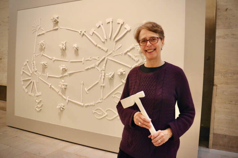 Virginia Maksymowicz holds one of the cast-plastic tools she created for her sculpture, ''Tools of the Trade,'' now installed in the North Waiting Room of William H. Gray III 30th Street Station. (Emma Lee/WHYY)