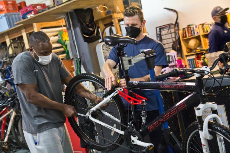 Eric Holte (left) learns to fix his bike with volunteer Michael Benko