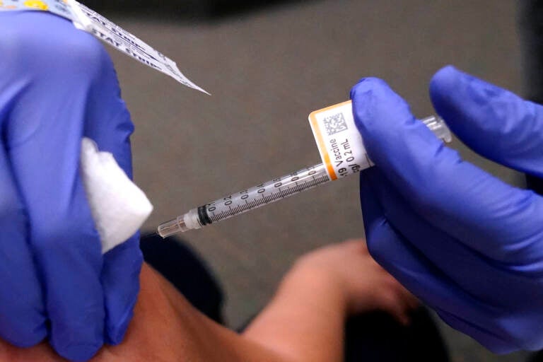 A closeup of a health worker's hands administering a COVID-19 vaccine