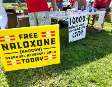 Signs advertise free Naloxone at a health event.