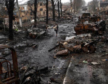 A woman walks amid destroyed Russian tanks in Bucha, in the outskirts of Kyiv, Ukraine, Sunday, April 3, 2022.