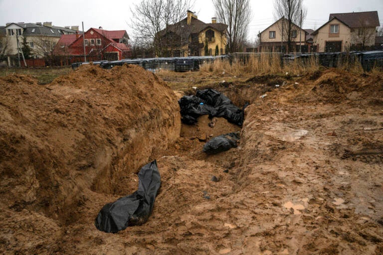 Bodies lie in a mass grave in Bucha, on the outskirts of Kyiv, Ukraine, Sunday, April 3, 2022. Ukrainian troops are finding brutalized bodies and widespread destruction in the suburbs of Kyiv, sparking new calls for a war crimes investigation and sanctions against Russia. (AP Photo/Rodrigo Abd)