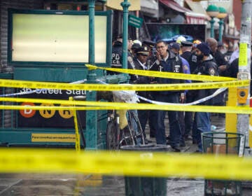 New York City Police Department personnel gather at the entrance to a subway stop in the Brooklyn borough of New York, Tuesday, April 12, 2022. Multiple people were shot and injured Tuesday at a subway station in New York City during a morning rush hour attack that left wounded commuters bleeding on a train platform. (AP Photo/John Minchillo)