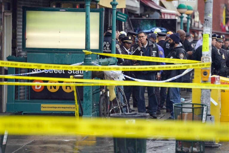 New York City Police Department personnel gather at the entrance to a subway stop in the Brooklyn borough of New York, Tuesday, April 12, 2022. Multiple people were shot and injured Tuesday at a subway station in New York City during a morning rush hour attack that left wounded commuters bleeding on a train platform. (AP Photo/John Minchillo)