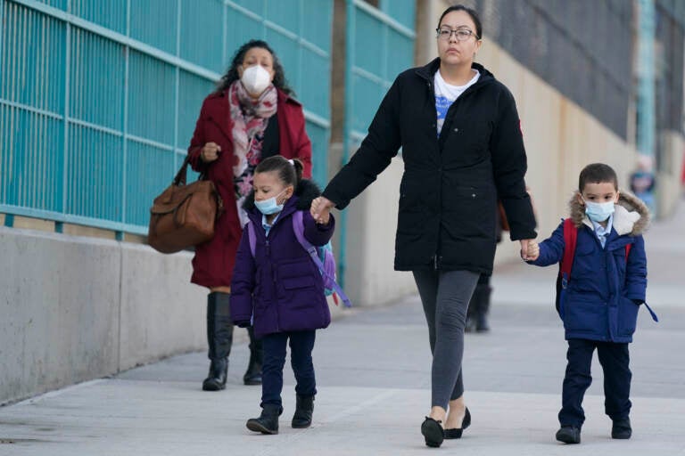 FILE - Children and their caregivers arrive for school in New York, Monday, March 7, 2022.  The Biden administration will extend for two weeks the nationwide mask requirement for public transit as it monitors an uptick in COVID-19 cases. The Centers for Disease Control and Prevention was set to extend the order, which was to expire on April 18, by two weeks to monitor for any observable increase in severe virus outcomes as cases rise in parts of the country.   (AP Photo/Seth Wenig, File)