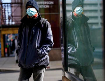 FILE - A person wearing a face masks to protect against the spread of the coronavirus walks in Philadelphia, Feb. 16, 2022.