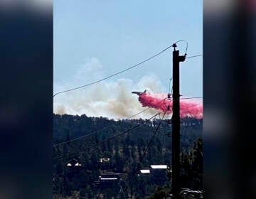 This photo provided by the Village of Ruidoso shows a fire fighting air tanker dropping fire retardant across the mountains near the Village of Ruidoso, N.M., on Wednesday, April 13, 2022. (Kerry Gladden/Village of Ruidoso via AP)