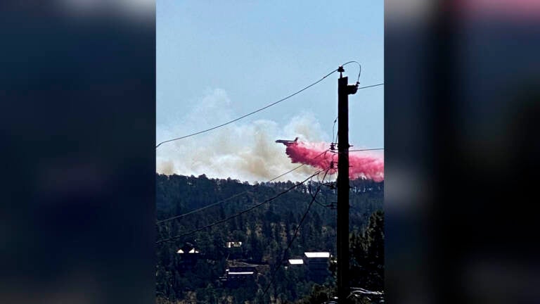 This photo provided by the Village of Ruidoso shows a fire fighting air tanker dropping fire retardant across the mountains near the Village of Ruidoso, N.M., on Wednesday, April 13, 2022. (Kerry Gladden/Village of Ruidoso via AP)