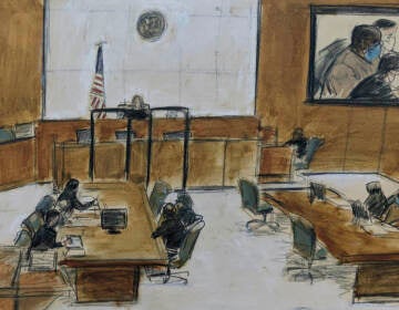 In this courtroom sketch, Frank James, seated at center of right table, and on left of the screen, upper right, appears during the brief proceeding in a federal court in the Brooklyn borough of New York, Thursday, April 14, 2022. James, accused of opening fire on a crowded subway train in Brooklyn, was ordered held without bail as prosecutors told a judge Thursday he terrified all of New York City