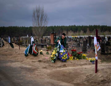 Volodymyr Bondar, 61, mourns next to the grave of her son Oleksandr, 32, after burying him at the cemetery in Bucha, in the outskirts of Kyiv, Ukraine on Saturday, April 16, 2022. (AP Photo/Emilio Morenatti)