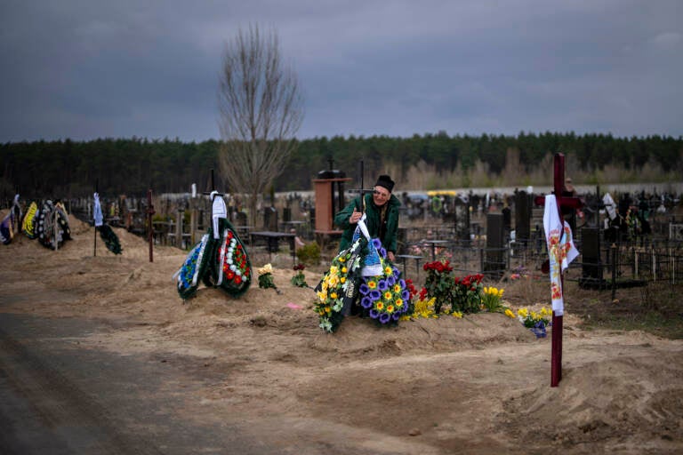 Volodymyr Bondar, 61, mourns next to the grave of her son Oleksandr, 32, after burying him at the cemetery in Bucha, in the outskirts of Kyiv, Ukraine on Saturday, April 16, 2022. (AP Photo/Emilio Morenatti)