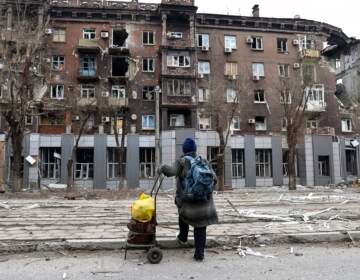 A person stands in front of a severely damaged building in Mariupol, Ukraine.