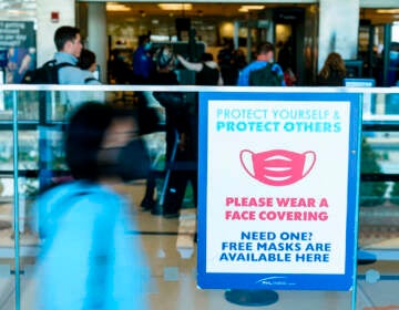 A sings is posted urging travelers to wear a protective masks as a precaution against the spread of the coronavirus