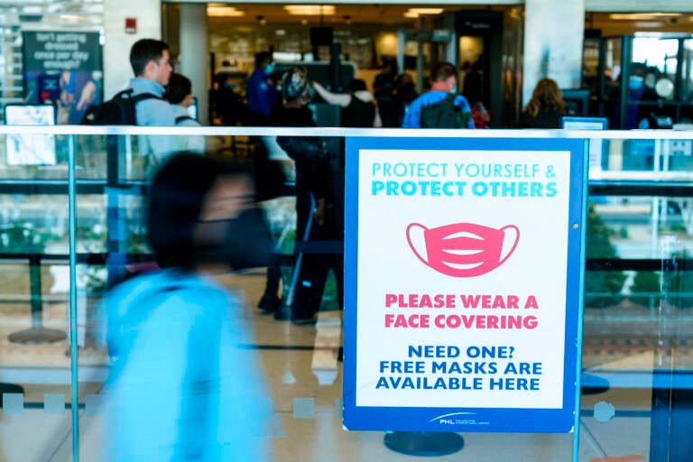 A sings is posted urging travelers to wear a protective masks as a precaution against the spread of the coronavirus