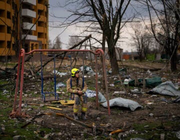A firefighter sits on a swing next to a building destroyed by a Russian bomb in Chernihiv on Friday, April 22, 2022. (AP Photo/Emilio Morenatti)