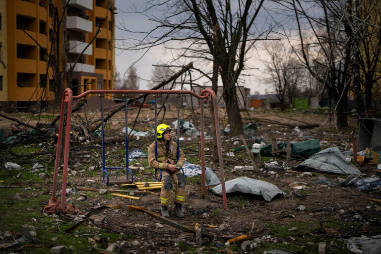 A firefighter sits on a swing next to a building destroyed by a Russian bomb in Chernihiv on Friday, April 22, 2022. (AP Photo/Emilio Morenatti)