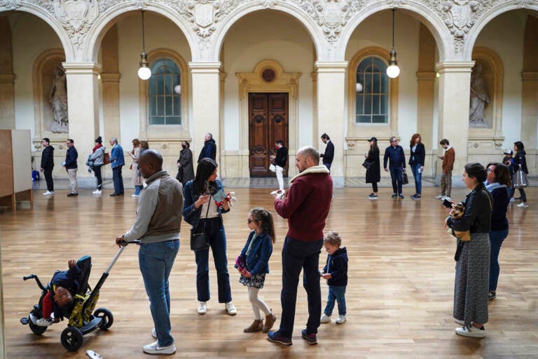 People queue to vote at a polling station in Lyon, central France, Sunday, April 24, 2022. France began voting in a presidential runoff election with repercussions for Europe's future, with centrist incumbent Emmanuel Macron the front-runner but fighting a tough challenge from far-right rival Marine Le Pen.