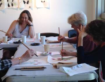 People are gathered around a table with art supplies.