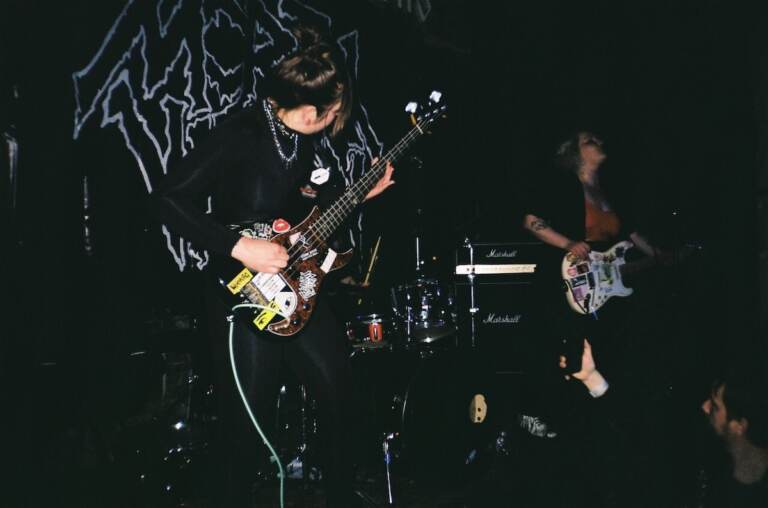 A member of Death Pill, an all-female Ukrainian punk band, plays electric guitar on stage.