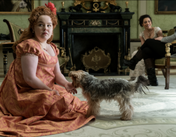 Nicola Coughlan sitting on a living romm rug with a dog by her hand