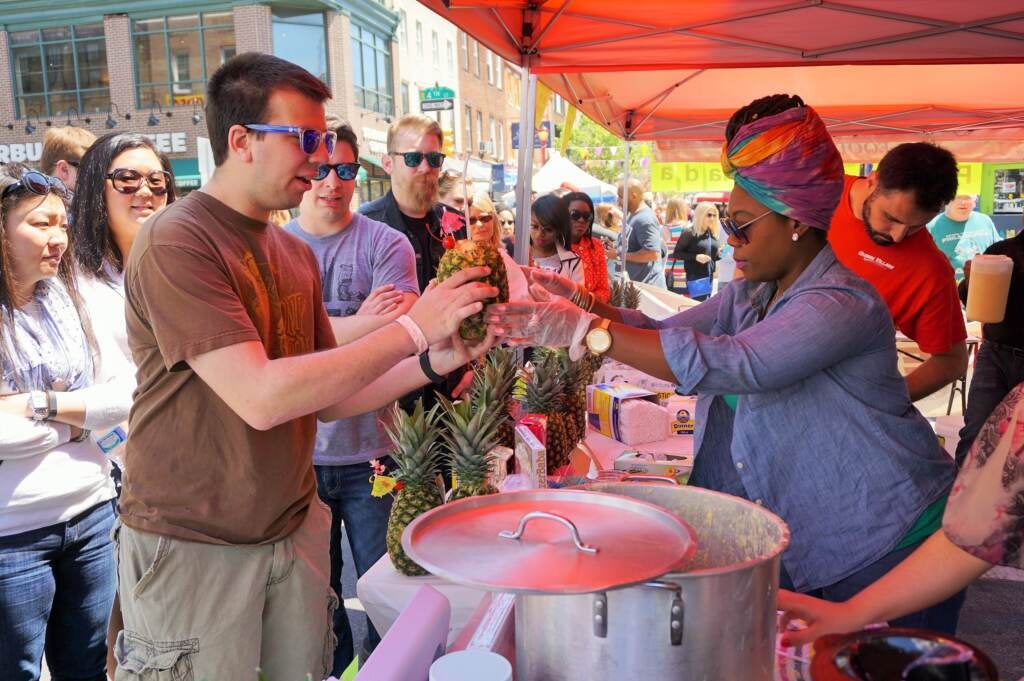 A person offers another person food at the South Street Festival.